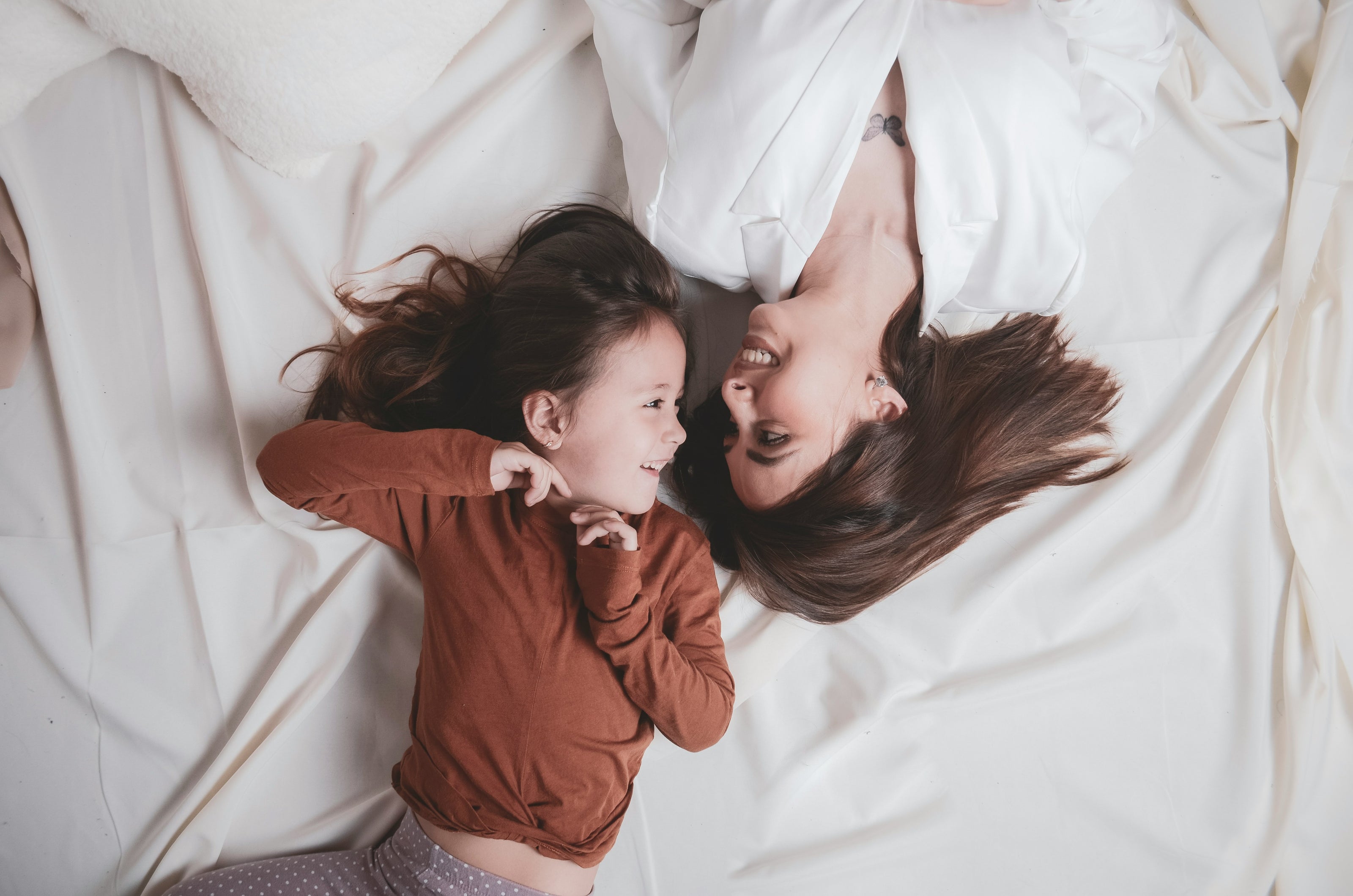 Mother and child relaxing together on bed, symbolizing comfort and wellness for Resture sleep and relaxation brand